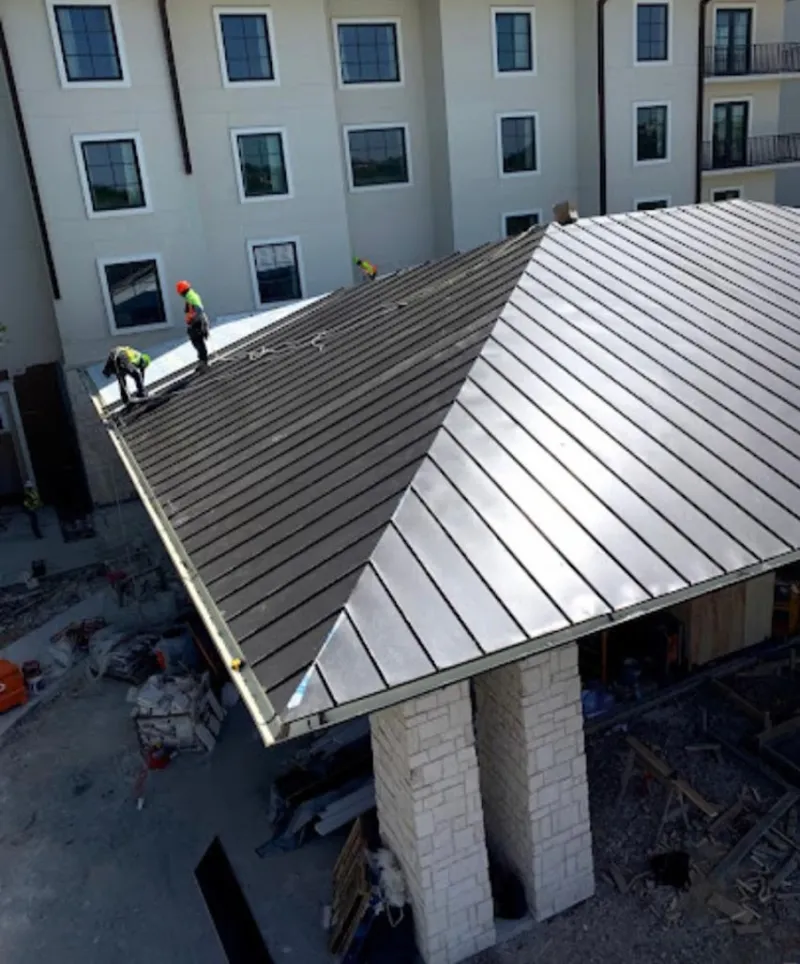 Crew installing standing seam metal roof panels on a commercial project in Lodi